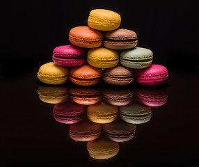 Heap of colorful macarons on reflecting black background