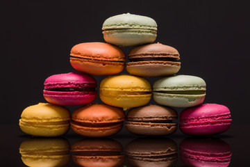 Heap of colorful macarons on black background