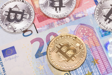 Golden and silver bitcoin coins on euro banknotes