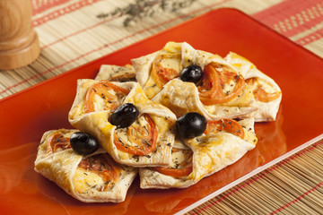 mini pizzas with tomatoes cheese and back olives on red plate, modern presentation
