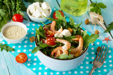 Festive appetizer. Salad with shrimps, feta cheese, arugula, cherry tomato and sesame on the festive Easter table.