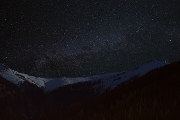 Mountain peaks in the background of the milky way. Night landscape with starry sky