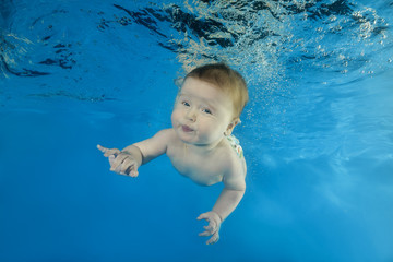 Fototapeta na wymiar little boy learns dives underwater in the pool