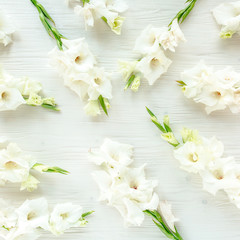 Flowers texture made of white gladioluses on wooden white background. Floral pattern of gladioli holiday greeting card. Flat lay, top view. Flowers texture