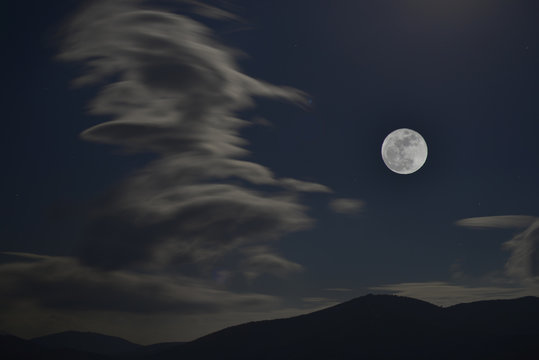 Luna llena en la noche oscura con nubes blancas sobre el horizonte