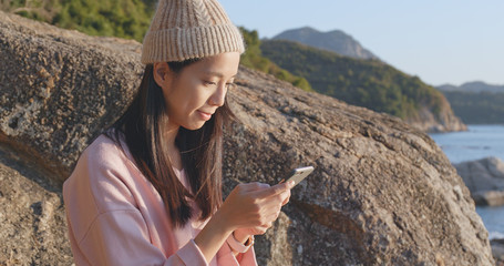 Woman using cellphone with seascape background