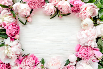 Floral pattern, frame made of beautiful pink peonies on wooden white background. Flat lay, top...