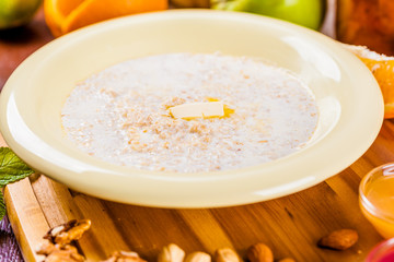 Oatmeal porridge with nuts, jam and fruits on wooden board