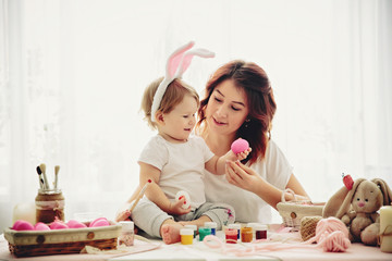 Obraz na płótnie Canvas mother and daughter painting eggs for Easter