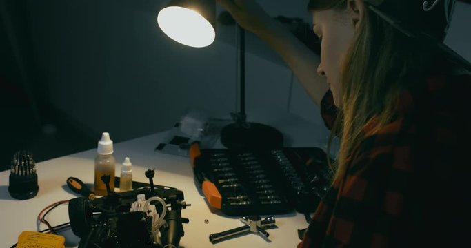 Young attractive teen girl assembling toy RC car at home in the evening. Hobby concept. 4K UHD