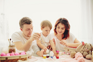 Obraz na płótnie Canvas Mother, father and daughters are painting eggs. Happy family are preparing for Easter. 