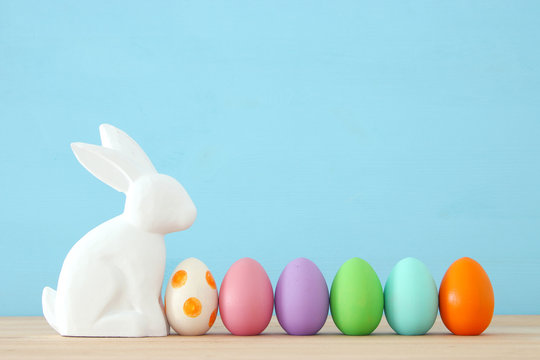 Cute bunny next to easter colorful eggs over colorful background.