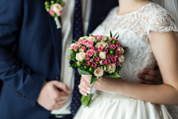 Obraz na płótnie Canvas Bride holding a wedding bouquet in the hands standing near groom