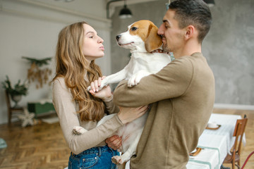 Young caucasian couple with beagle in dining room