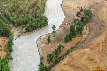 Aerial view of camping site near mountain river with cars and tents