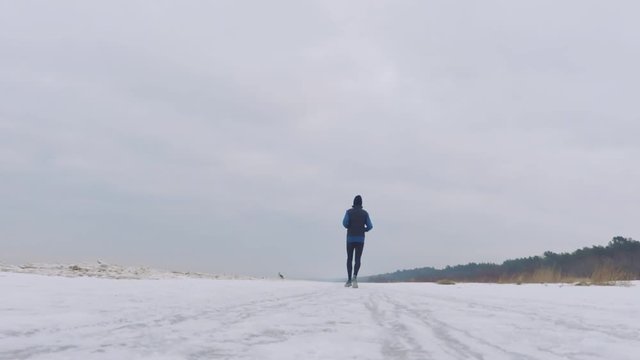 a man running in winter on a beautiful snowy beach