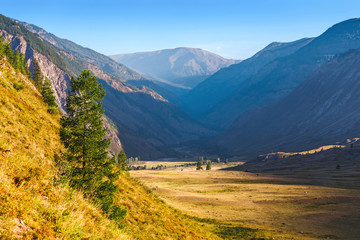 A classic Altai landscape with snow-capped rocky mountains and vast pastures with lush grass