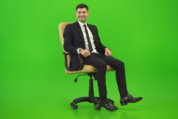 The happy man sit of the chair on the green background