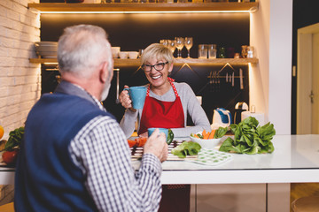 Senior couple preparing lunch together in kitchen.