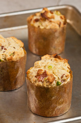 Three, hot, freshly baked, homemade, sweet corn, bacon and jalapeño muffins in paper forms, cooling on a baking sheet