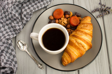 Croissant,coffee,nuts and dried apricots  on the  grey plate.View from above.