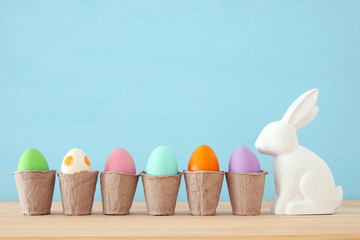 Cute bunny next to easter colorful eggs over colorful background.