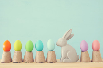 Cute bunny next to easter colorful eggs over colorful background.
