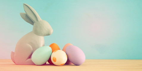 Cute bunny next to easter colorful eggs over colorful background.