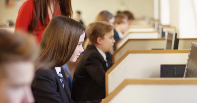 4k, A beautiful young teacher leaning over her pupil and pointing to something on a computer screen. Slow motion.