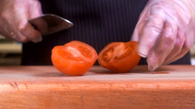 The chef in black apron cuts vegetables.