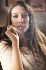 Young caucasian woman smoking a cigarette inside a coffee shop