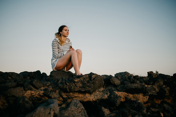 Girl sitting on the rock in the evening