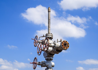 Oil well after repair in mud and puddles. Oil well wellhead equipment. Hand valve with handwheel...