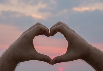 Plakat Man hand heart shape in sunset on the beach. Love concept