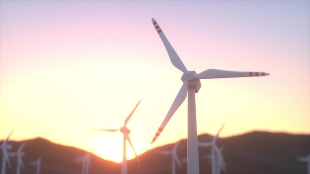Windrad dreht sich im Sonnenuntergang mit Bergen im Hintergrund