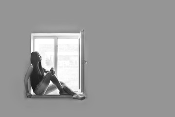 Fototapeta na wymiar Model sits on a window sill against a gray wall