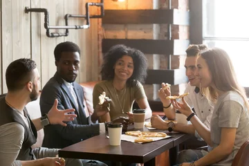 Fototapete Pizzeria Multiethnische afrikanische und kaukasische Freunde, die in der Pizzeria Pizza essen, verschiedene junge Leute genießen italienisches Essen beim Treffen, gemischtrassige Studenten, die sich beim gemeinsamen Mittagessen im Café unterhalten