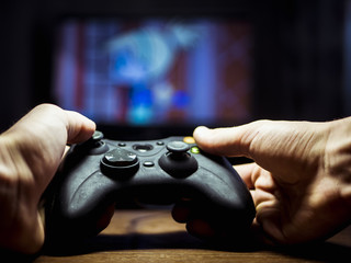 video game controller joystick in the hands playing on a tv © Mihail