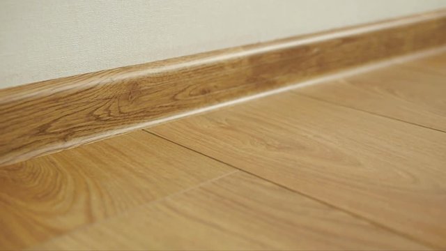 The camera moves along the floor, covered with laminated parquet with a brown wooden texture