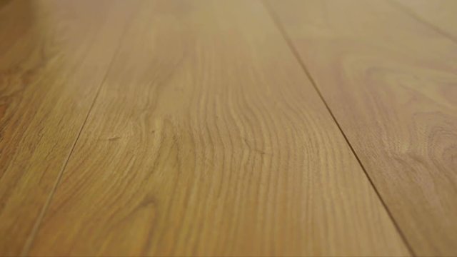 The camera moves along the floor, covered with laminated parquet with a brown wooden texture