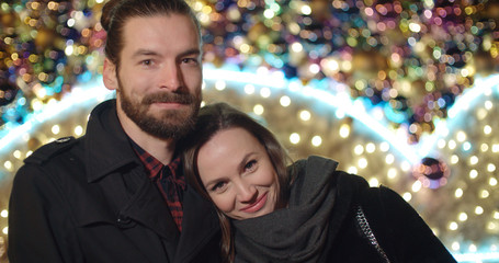 Fototapeta premium Beautiful young couple on a date standing in a city street at night, portrait.