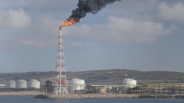 Flare stack and smoke of petrochemical refinery on sea shore