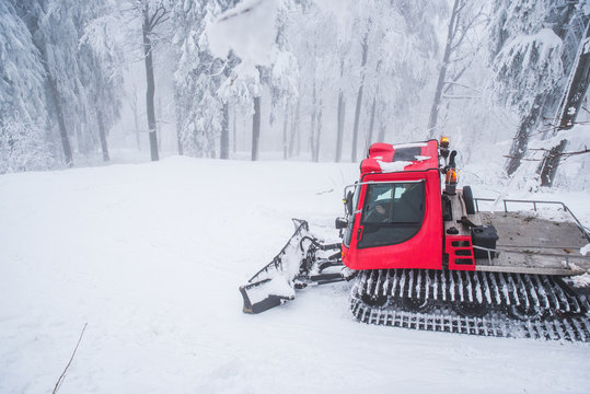 Red snow tractor in white winter forest, ski resort
