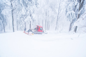 Snow tractor in white winter forest prepare track for nordic ski cross country race