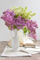 still life with a bouquet of lilac in a vase, book, postcards