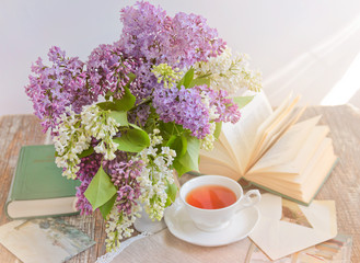 still life with a bouquet of lilac, a cup of tea, a book and postcards