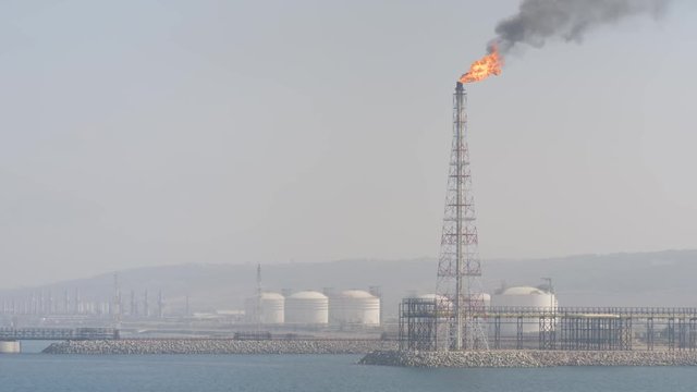 Burning gas on tower of marine terminal in haze