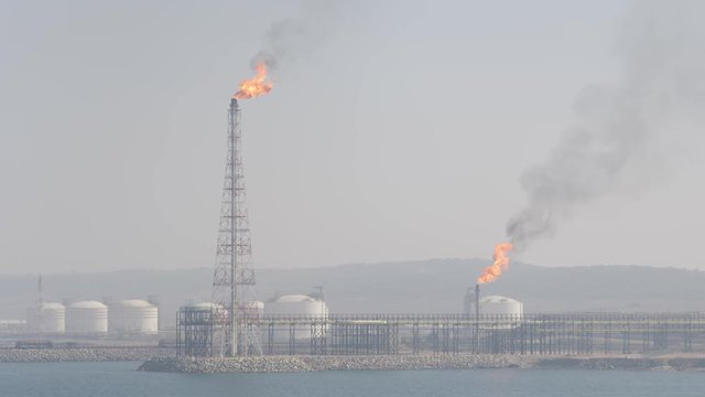 Gas flare of petrochemical refinery on sea shore