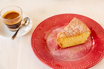 A piece of delicious carrot pie on a red shiny plate. Part of a homemade cupcake on a plate with black coffee. Homemade pie on a ceramic plate on a white wooden table.