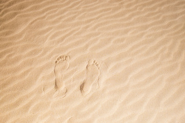 Fototapeta na wymiar pair of man footsteps on the sand at the beach